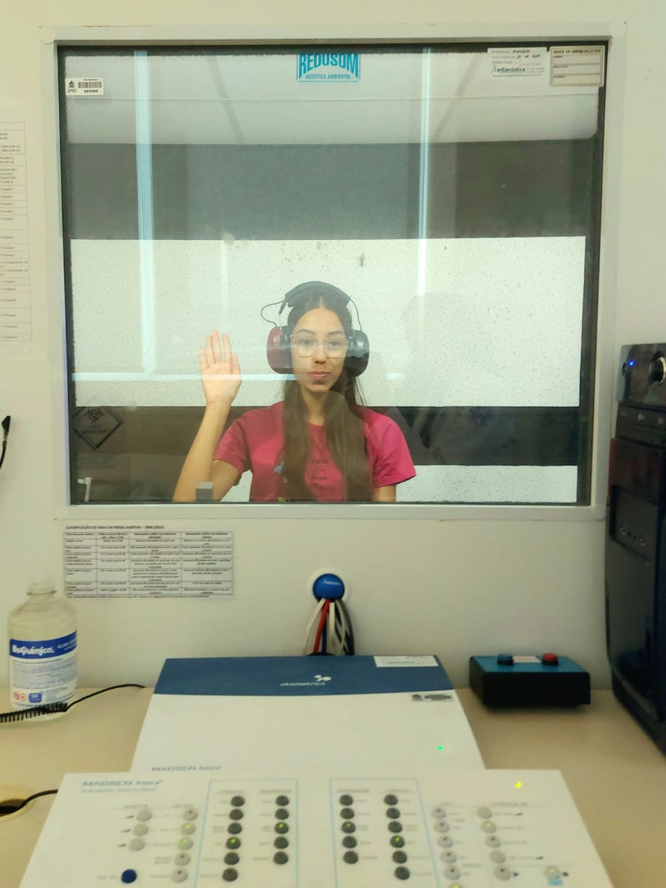Pessoa realizando exame de audiometria em cabine acústica
