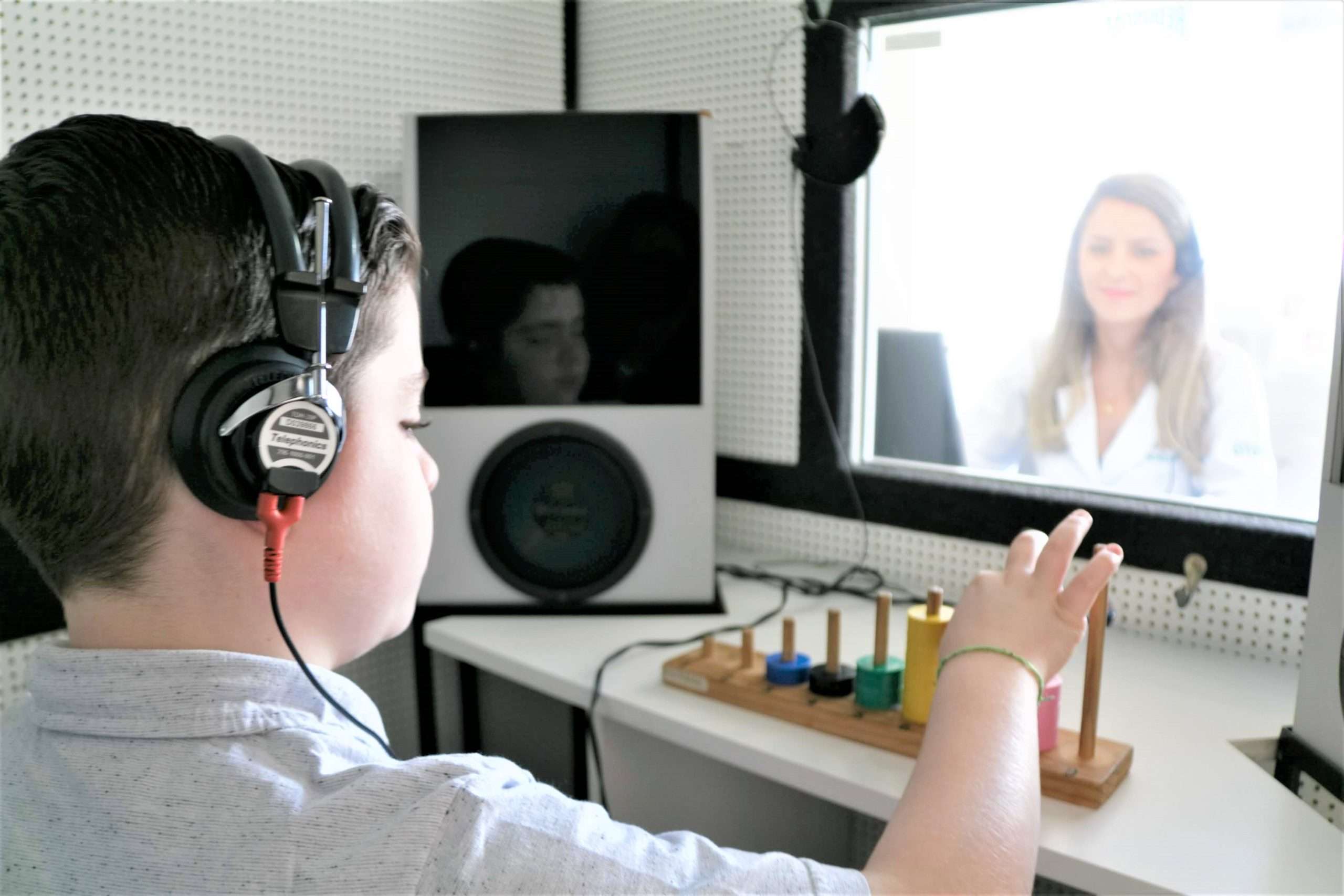 Pessoa realizando avaliação auditiva com fones em cabine acústica